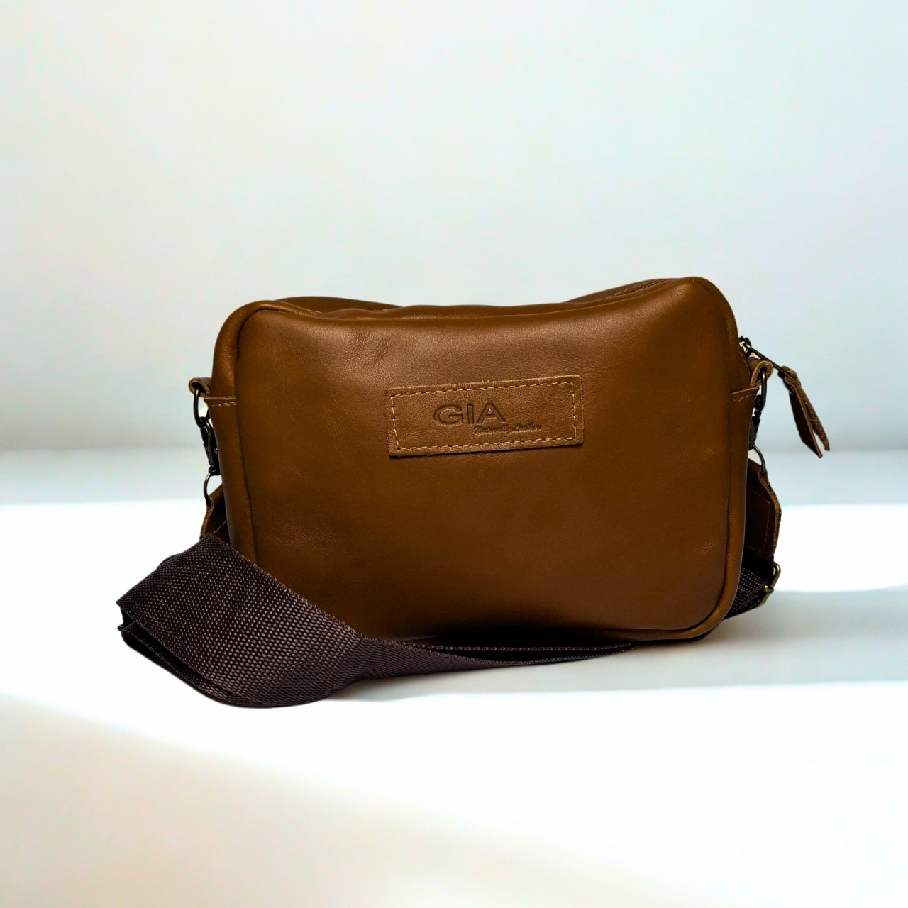 Gia Camera Bag in Texas Toffee leather โ compact crossbody with zip closure, rear magnetic pocket, adjustable strap, and embossed GIA logo patch 1