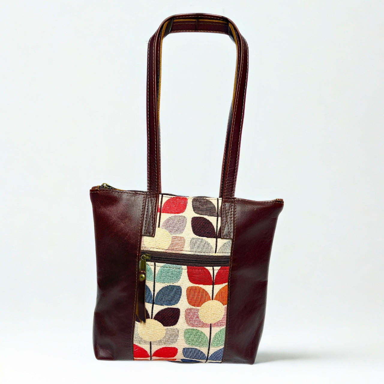 Gia dark brown leather tote with vibrant tulip fabric panel, front zip pocket, and dual handles.