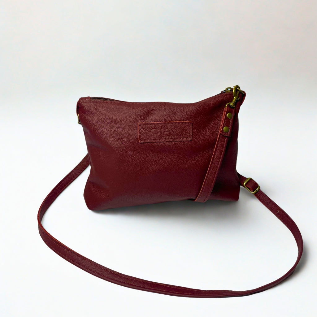 Gia dark red crossbody bag in genuine leather with adjustable strap, antique brass hardware, and embossed logo – compact designer handbag for everyday wear and evening outings.