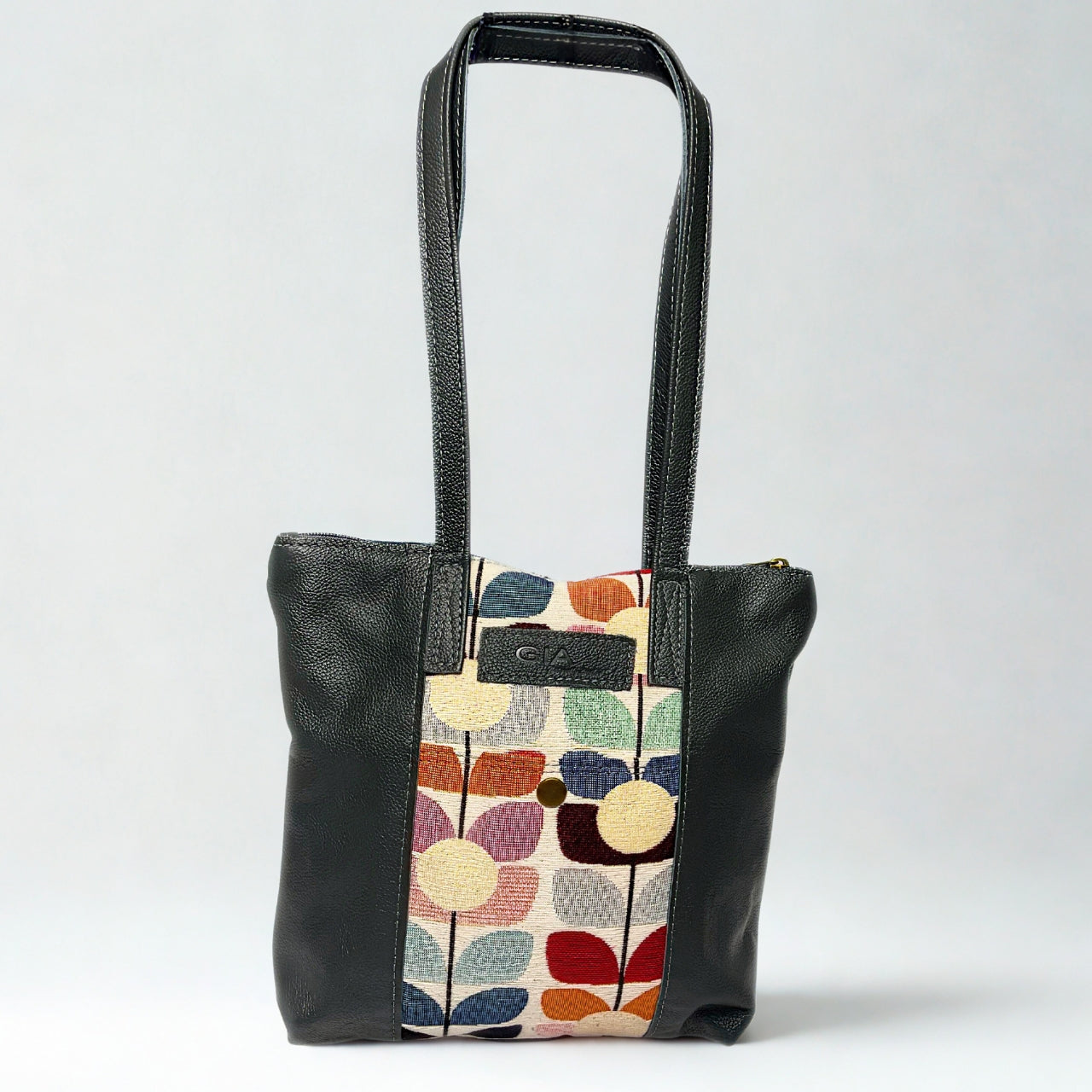 Gia grey leather tote with tulip fabric front panel, zip pocket, and dual shoulder handles.