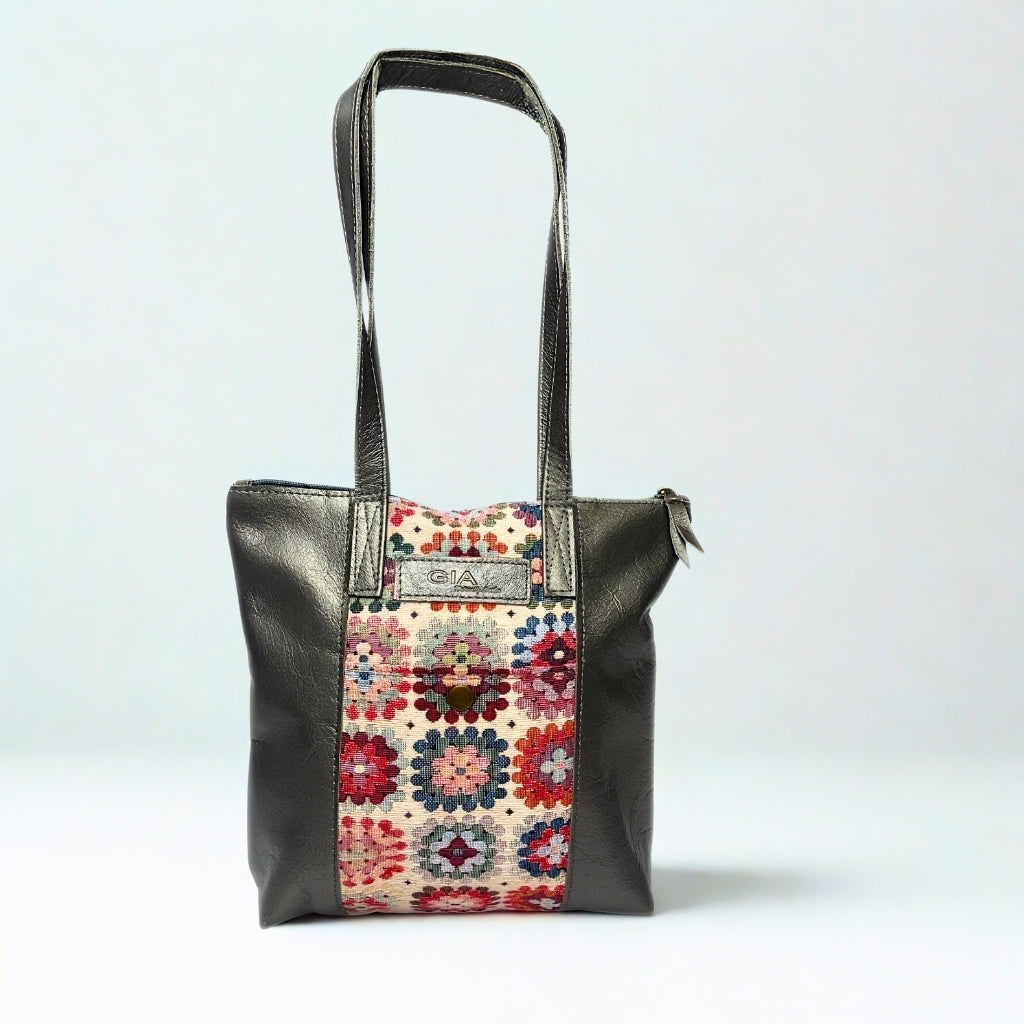 Gia pewter leather tote bag with woven tapestry panel, dual shoulder straps, antique brass hardware, and embossed logo – spacious crochet-inspired handbag for work, travel, and everyday style.