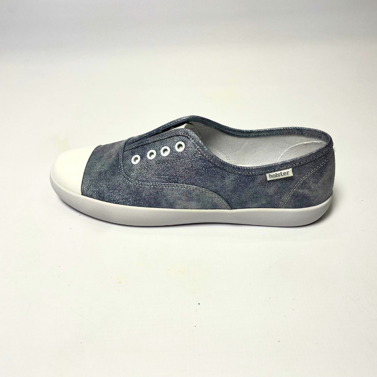 Holster Lulu Denim Shimmer Sneaker β Vegan-friendly, cruelty-free slip-on sneaker with a metallic PU upper and white PU toe cap. Features elastic gusset for easy wear, eyelet embellishments, and a soft PU foam insole for comfort. Designed with a non-slip rubber outsole and antibacterial properties. 3