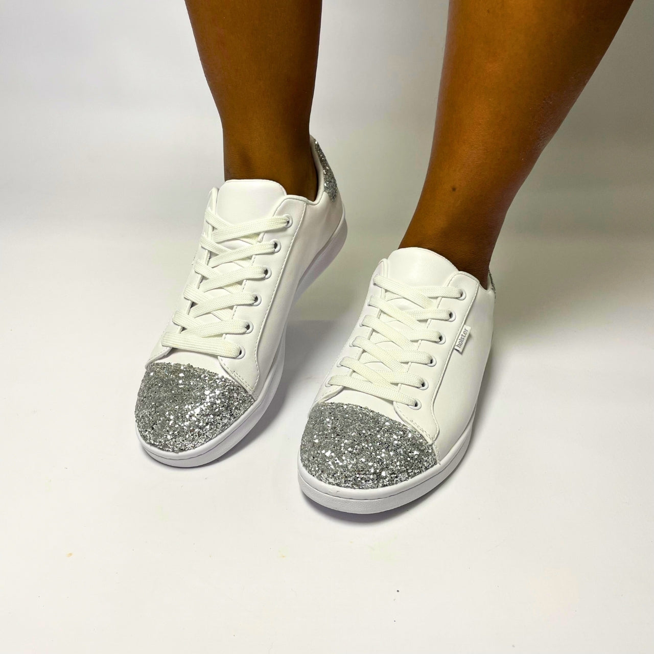 Holster Stardust White Sneaker – Vegan-friendly, PETA-approved sneaker featuring a glitter toe and heel cap. Designed with a soft padded PU upper, cushioned PU foam insole, and non-slip rubber outsole for comfort and durability. Lightweight, antibacterial, and flexible. Adjustable polyester shoelaces for a secure fit. 1
