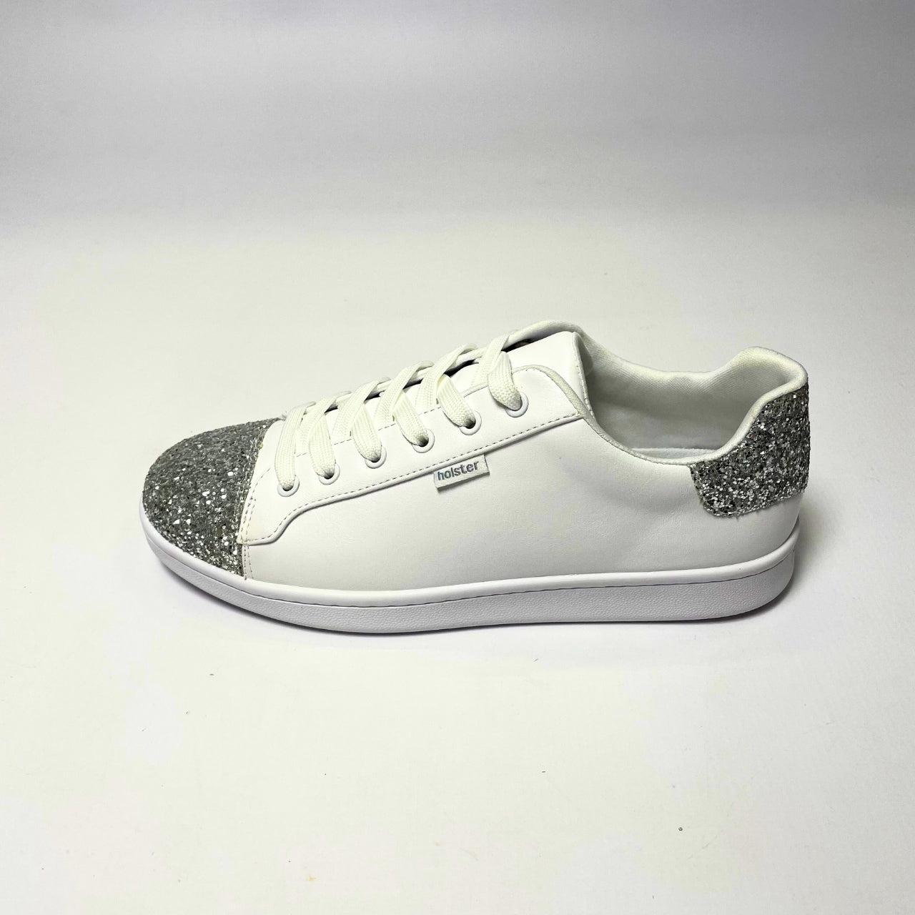 Holster Stardust White Sneaker – Vegan-friendly, PETA-approved sneaker featuring a glitter toe and heel cap. Designed with a soft padded PU upper, cushioned PU foam insole, and non-slip rubber outsole for comfort and durability. Lightweight, antibacterial, and flexible. Adjustable polyester shoelaces for a secure fit. 3