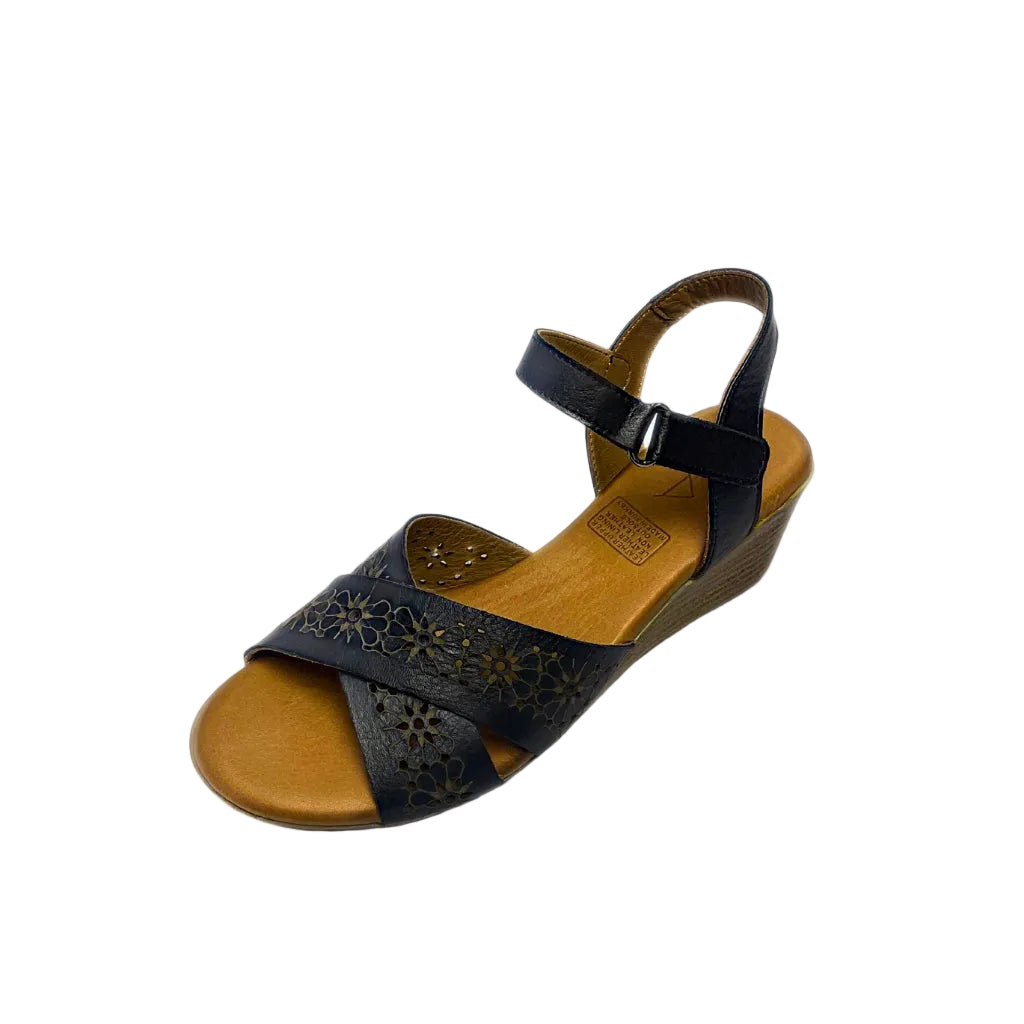 Gia black leather wedge sandals with laser-cut floral cross-over straps, cushioned insole, ankle strap, and natural wood finish heel – elegant women’s summer wedges for comfort and style.
