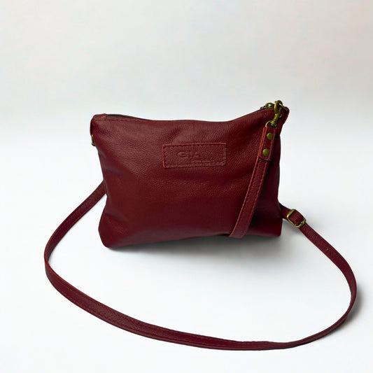 Gia dark red crossbody bag in genuine leather with adjustable strap, antique brass hardware, and embossed logo – compact designer handbag for everyday wear and evening outings.
