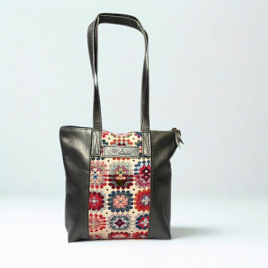 Gia pewter leather tote bag with woven tapestry panel, dual shoulder straps, antique brass hardware, and embossed logo – spacious crochet-inspired handbag for work, travel, and everyday style.