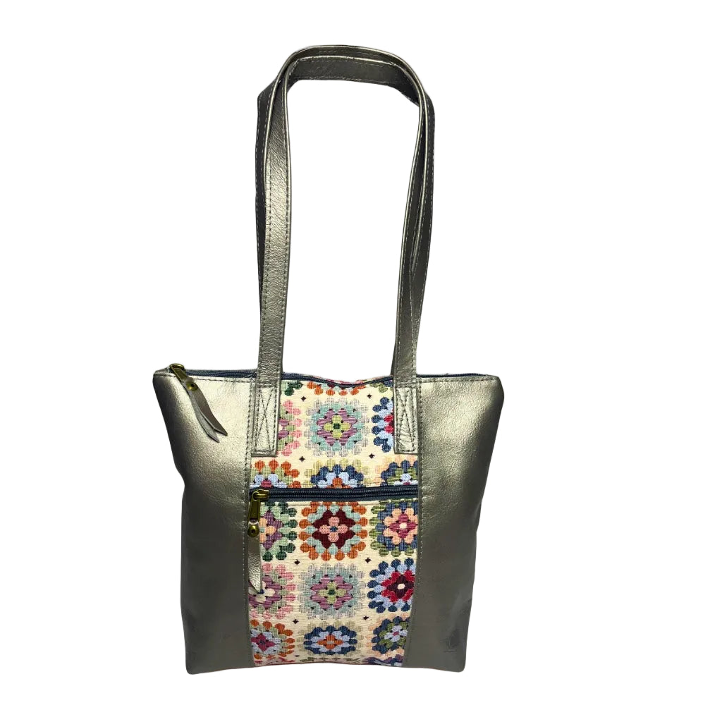 Gia pewter leather tote bag with woven tapestry panel, dual shoulder straps, antique brass hardware, and embossed logo – spacious crochet-inspired handbag for work, travel, and everyday style.