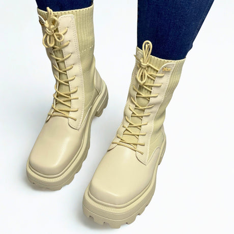 Plum beige combat-style boot with ribbed knit shaft, chunky lug sole, and lace-up front.